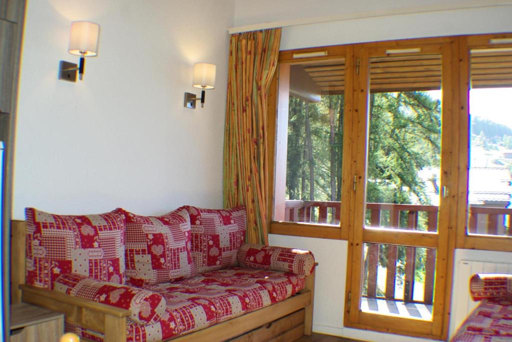 un salon avec un canapé et une fenêtre dans l'établissement Résidence Le Hameau du Sauget - maeva Home - Appartement duplex 2 pièces 4 personnes - Sélection MAE-2604, à La Plagne Tarentaise