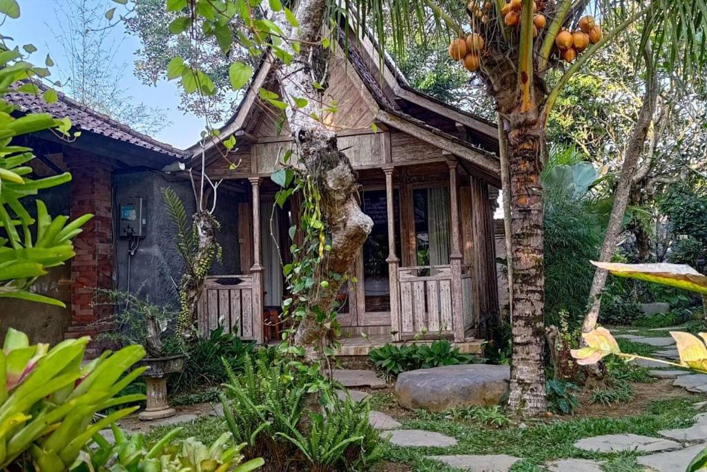 a small wooden house with a tree in front of it at Tangkas wooden house in Tampaksiring