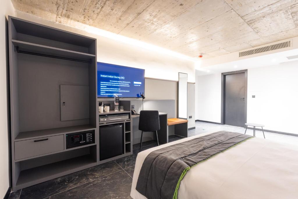 a bedroom with a large flat screen tv and a bed at The Londoner Hotel St. Julian's in St. Julianʼs