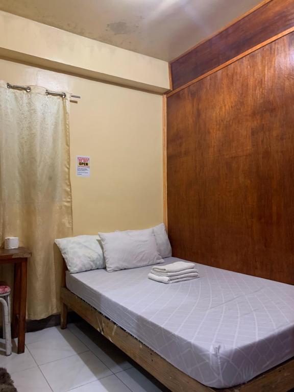 um pequeno quarto com uma cama e uma cabeceira em madeira em Querencia Inn em Banaue