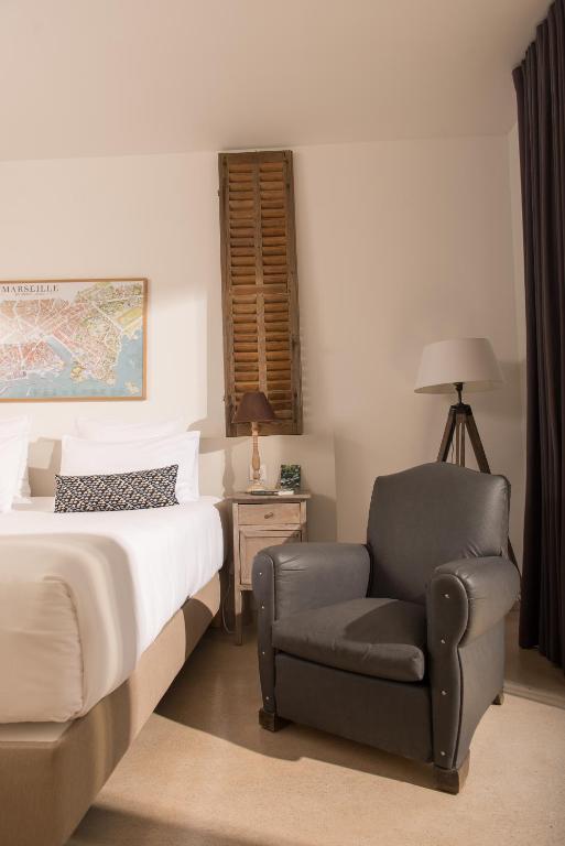 a bedroom with a bed and a chair at Hôtel 96 in Marseille
