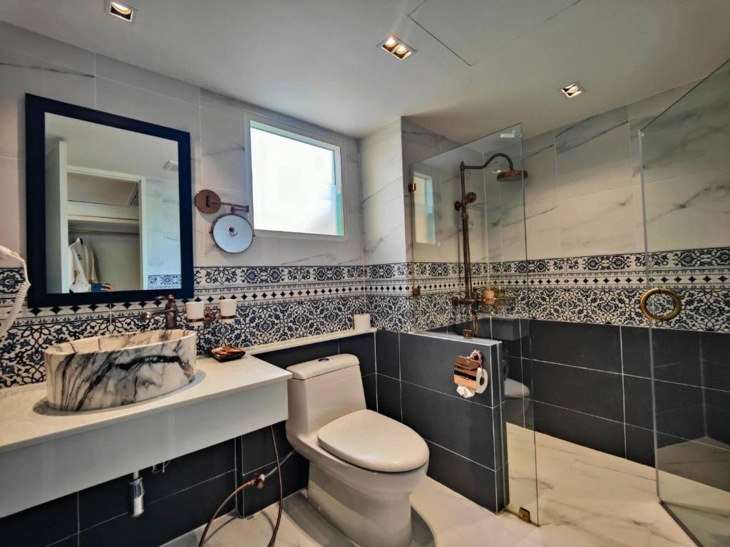 A marble-patterned bathroom with a walk-in shower, toilet, and vessel sink.