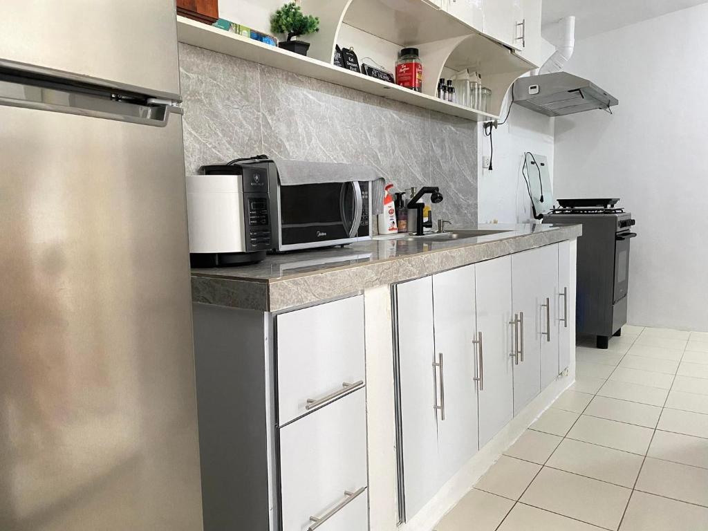 cocina con encimera y microondas en Cozy 2 Bedroom (Entire House) Pearson Residences, en Hulugan