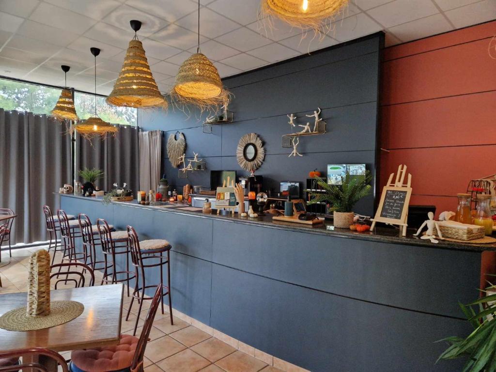 un restaurant avec un bar bleu avec des chaises et des tables dans l'établissement Tempo Hôtel, à Millau