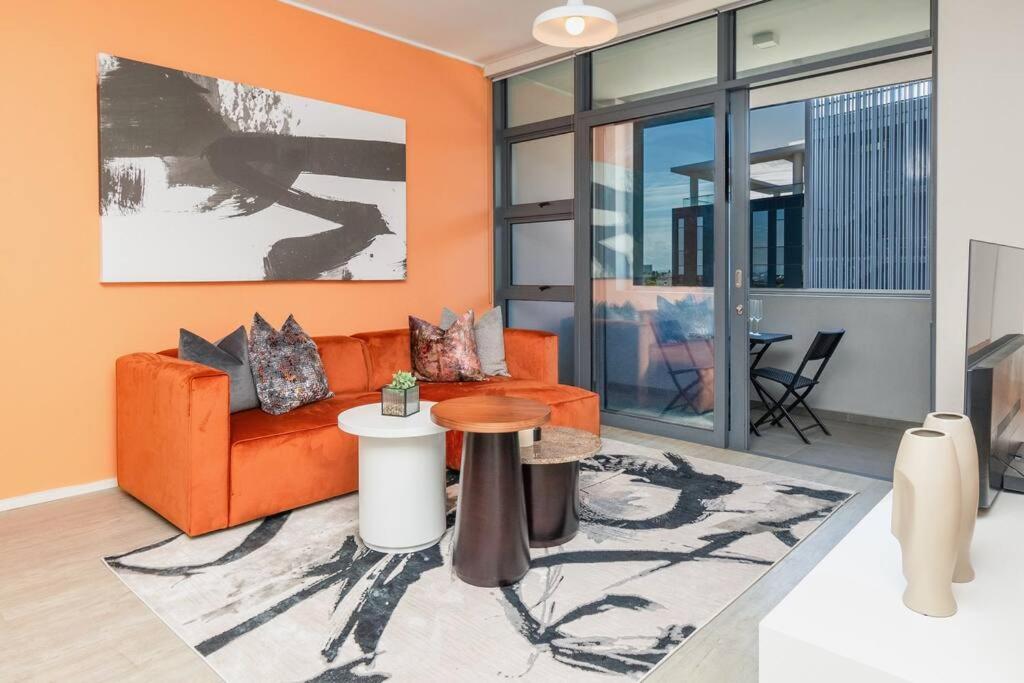 a living room with an orange couch and a table at Trendy Apartment in Century City in Cape Town