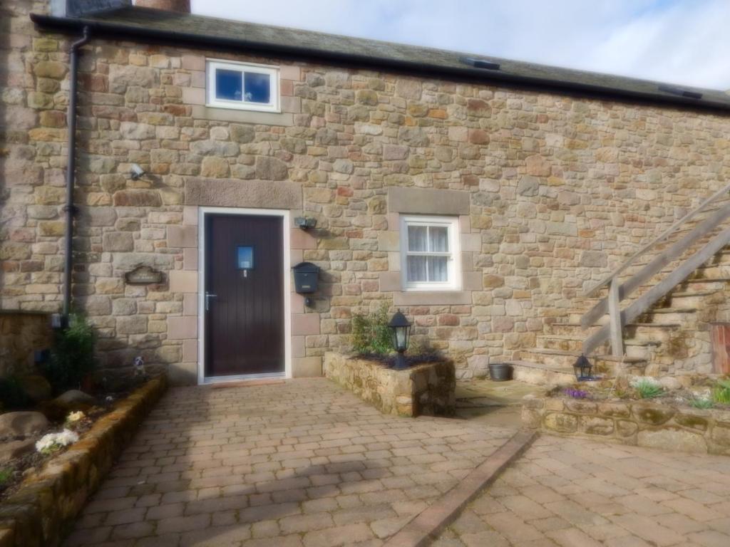 a brick house with a door and a staircase at The Old Barn Bed & Breakfast in Chathill