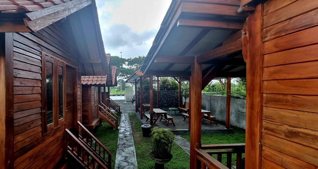 um alpendre de uma casa de madeira com uma mesa e bancos em Mayeka Transit Hostel Bandara Internasional Lombok em Praya