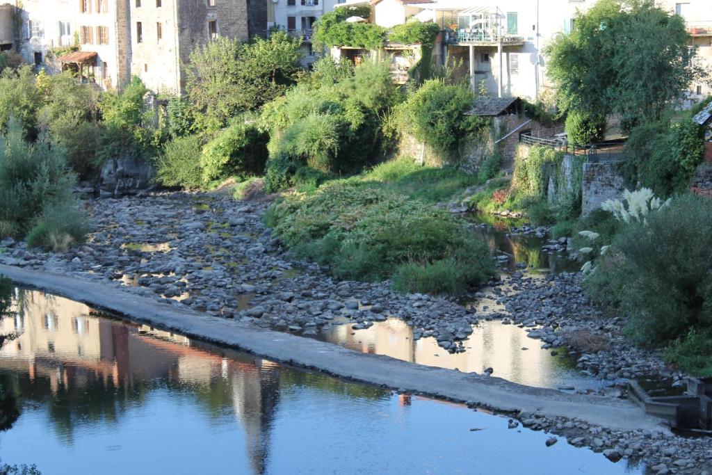 a river with rocks and buildings in the background at Chambre Bounty cuisine privée, salle d&#39;eau, terrasse, garage in Olliergues