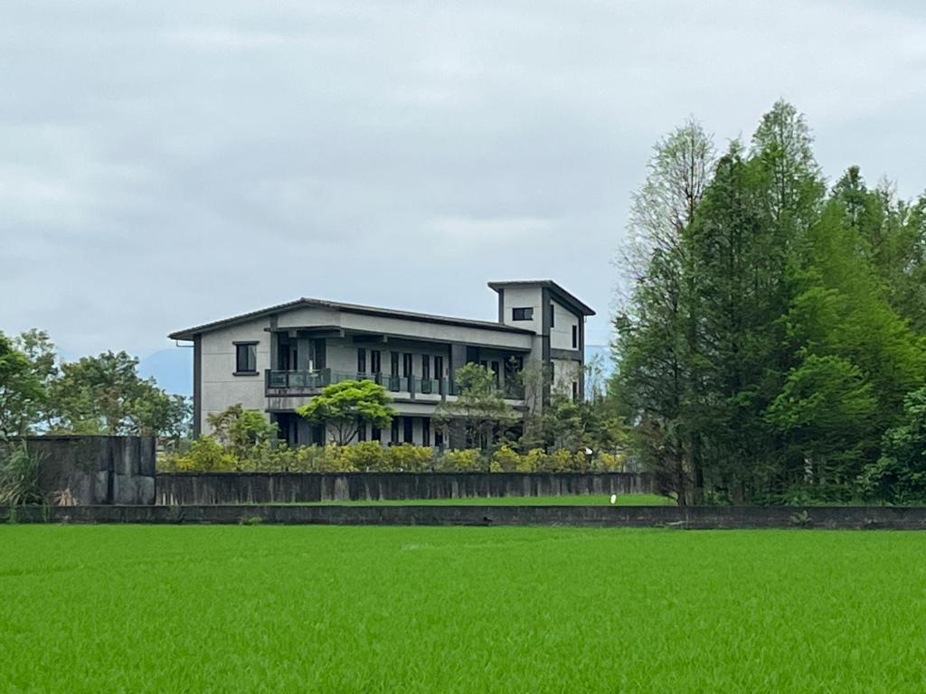 a house with a green field in front of it at Lakeforest B&B in Yuanshan