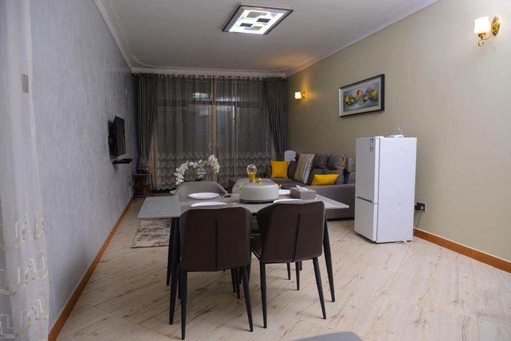 ein Esszimmer mit einem Tisch und einem weißen Kühlschrank in der Unterkunft 3 Bedroom Family Apartment in Namulanda