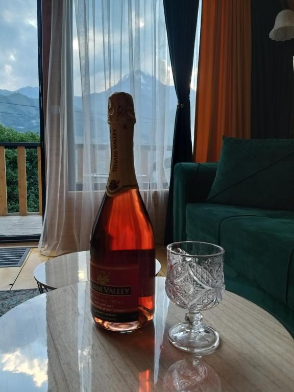 una botella de vino sentada en una mesa junto a una copa en Emotion Kazbegi en Kazbegi