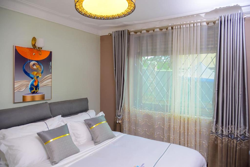 um quarto com uma cama branca e uma janela em 3 Bedroom Malaikanzi Apartment em Namulanda