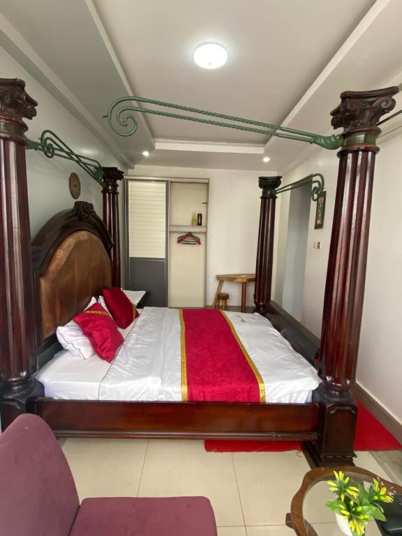 a bedroom with a large wooden bed with red pillows at Kantree House - Safari Suites in Kampala