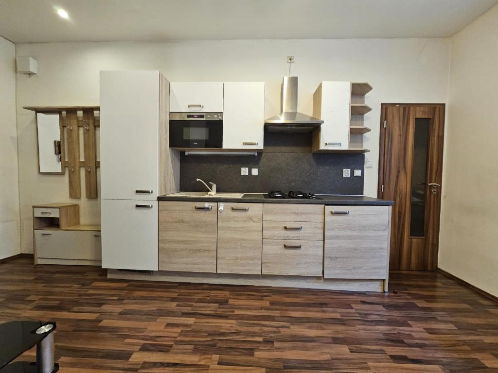 a kitchen with white cabinets and a wooden floor at Cozy Homestay at Andel Prague in Prague