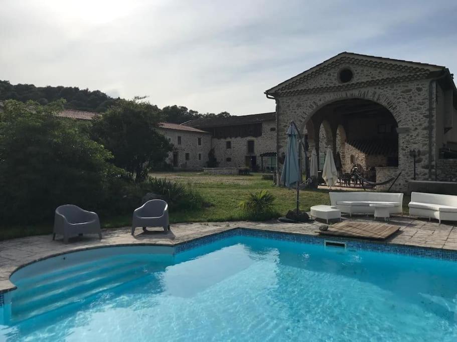 une piscine avec deux chaises et un parasol dans l'établissement Métairie du Château, à Aussillon