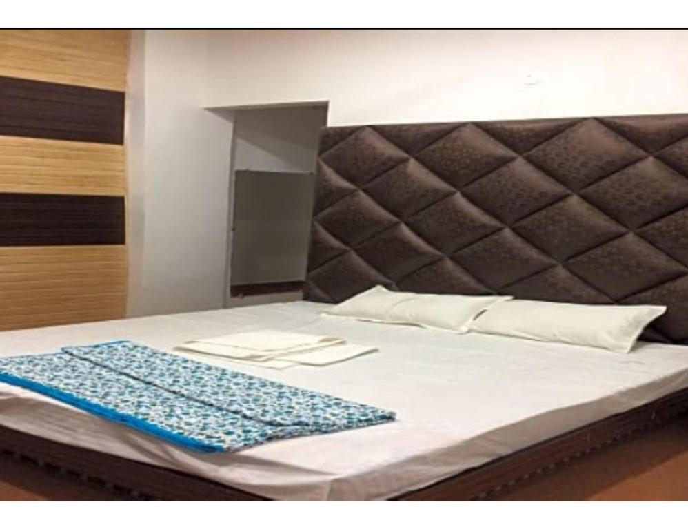 a bed with a gray headboard and a blue blanket on it at Hotel Royal, Amritsar in Amritsar
