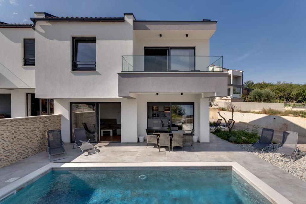 a house with a swimming pool in front of a house at Villa Rosemary -semi-detached villa with a pool and a panoramic view, close to a sandy beach - by TRAVELER tourist agency Krk in Risika