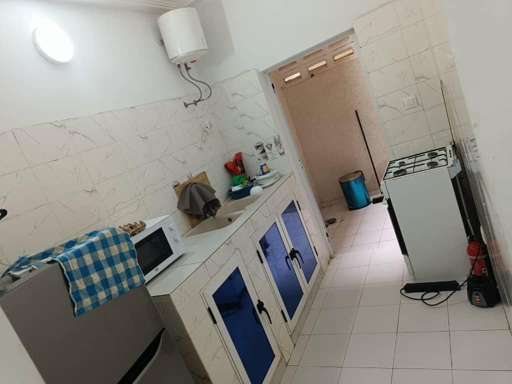 een kleine keuken met blauwe kasten en een koelkast bij TOTSI New World in Lomé
