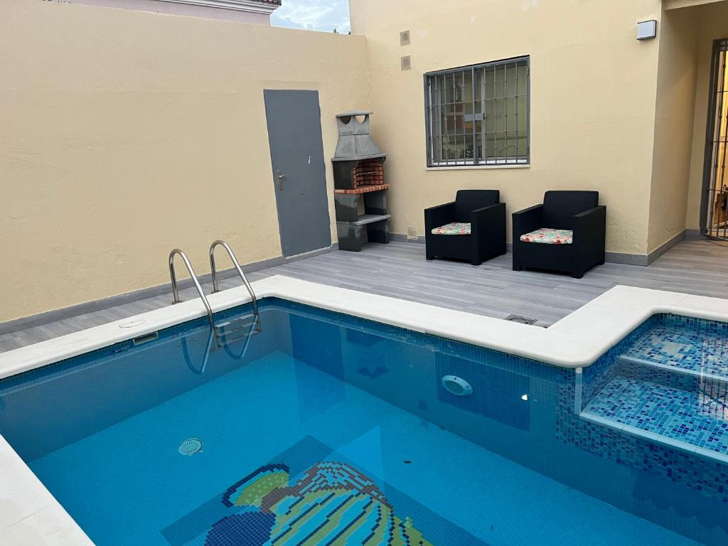 uma piscina com duas cadeiras e uma lareira em Ribera house Sevilla em Coria del Río