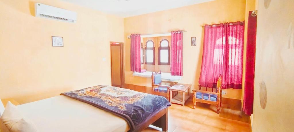 een slaapkamer met een bed, een bureau en ramen bij The Desert Blabla Hostel in Jaisalmer