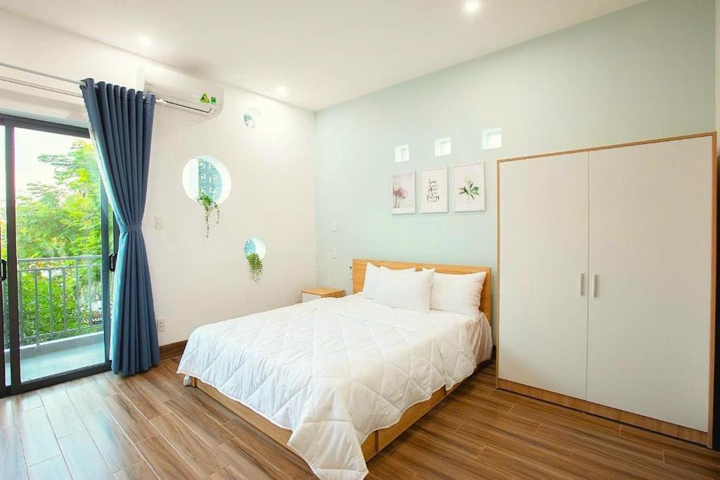 een slaapkamer met een wit bed en een glazen schuifdeur bij MNM apartment in Da Nang