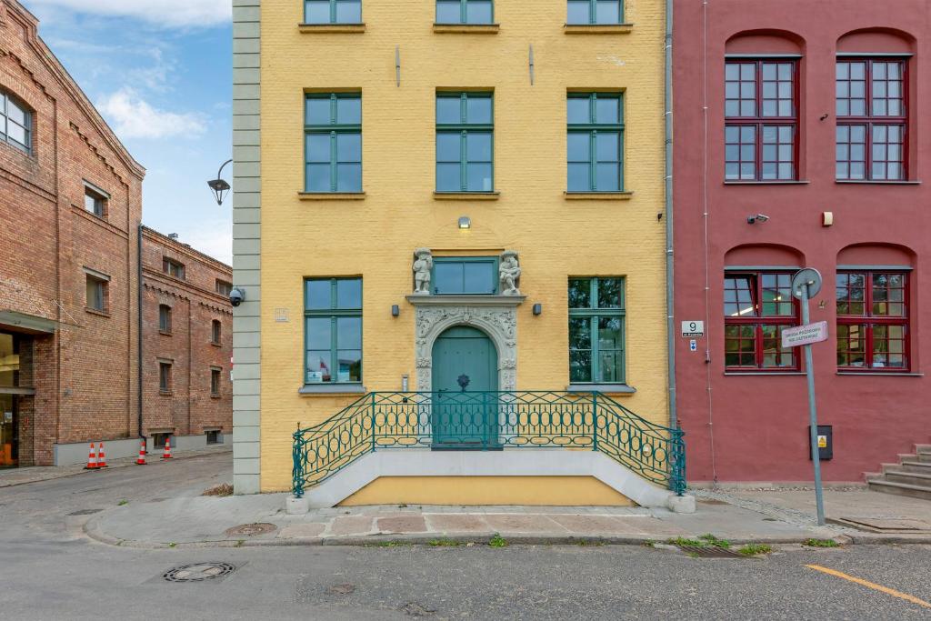 a yellow building with a blue door on a street at Historical Townhouse by Blue Mandarin in Gdańsk