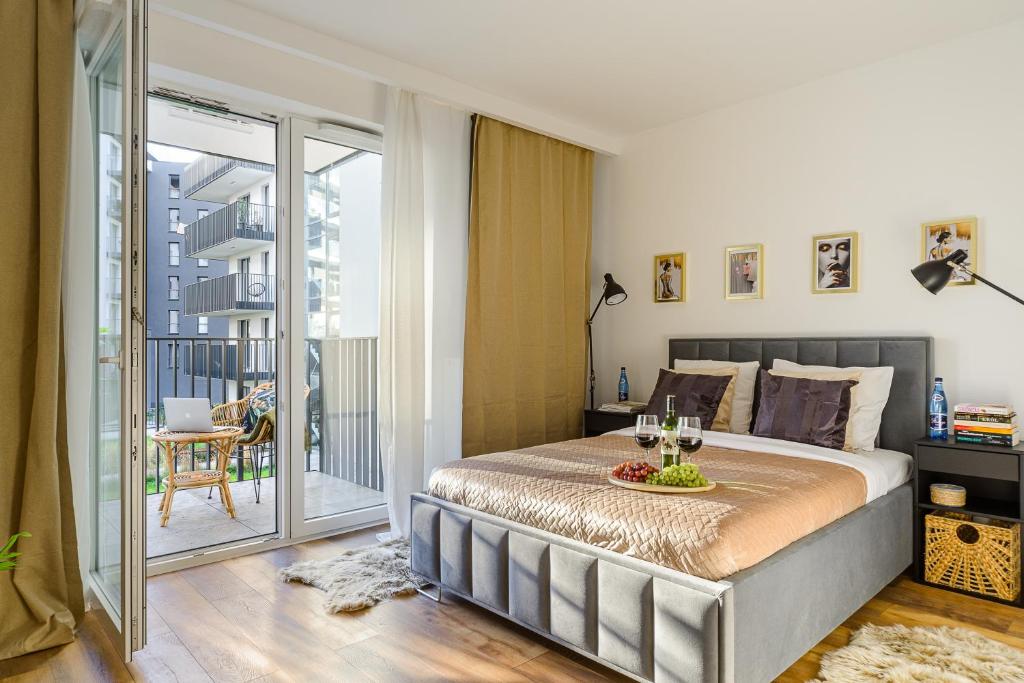 een slaapkamer met een groot bed en een balkon bij Lumina premium apartments with parking Manufactura in Łódź