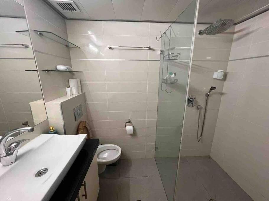 a bathroom with a glass shower and a toilet at Dream Studio in Herzliya