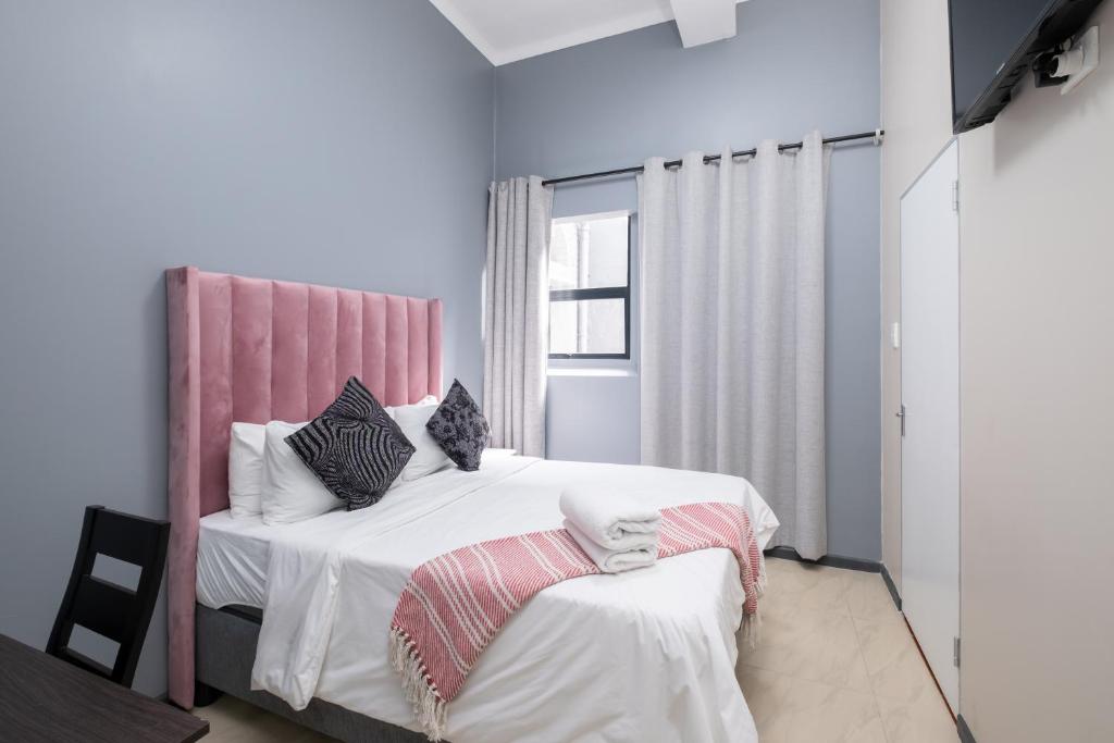 1 dormitorio con 1 cama grande y cabecero rosa en Cape palm royal guest house, en Ciudad del Cabo