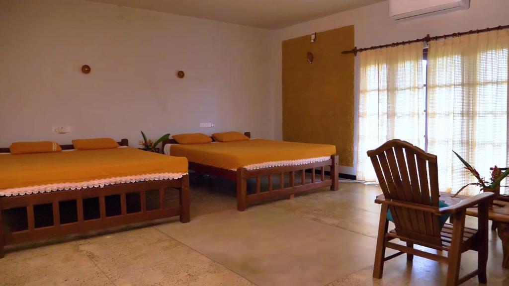 Habitación con 2 camas, mesa y silla en Manikgoda Tea Paradise en Matugama