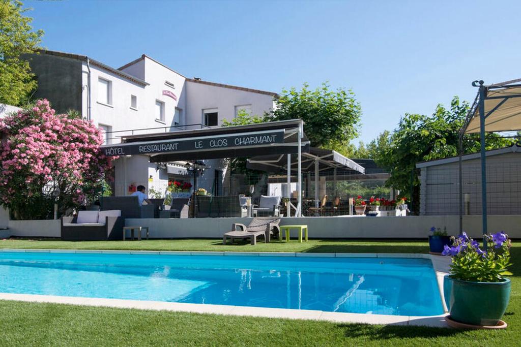 ein Pool in einem Hof neben einem Gebäude in der Unterkunft Hôtel Restaurant Le Clos Charmant in Vallon-Pont-dʼArc