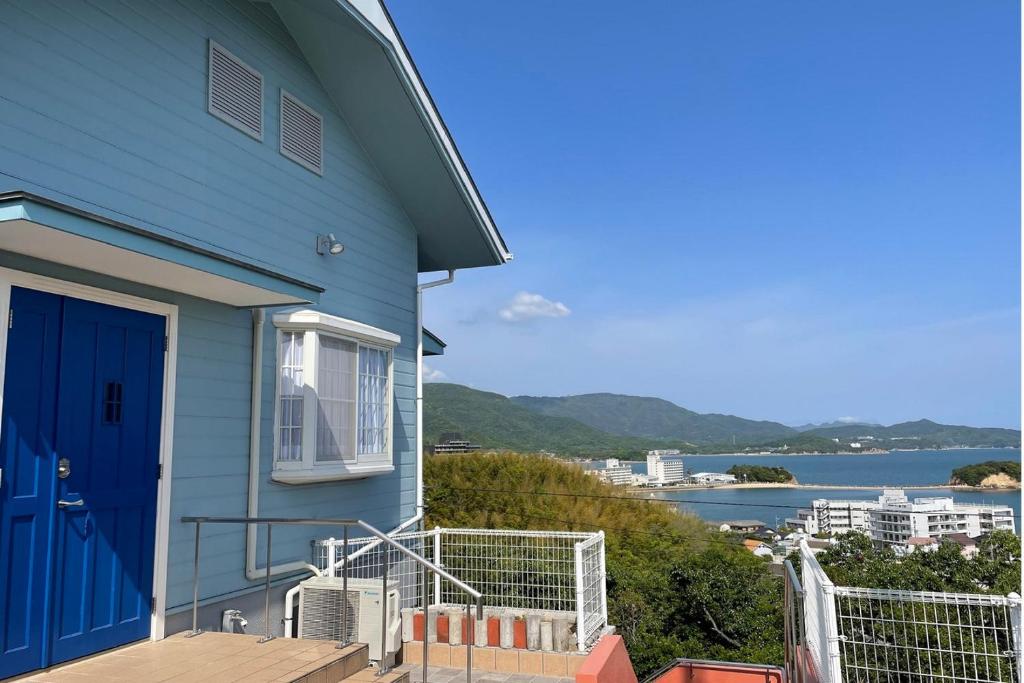 uma casa azul com uma porta azul e vista para a água em La Classe Angel Road 2 - Vacation STAY 71507v em Fuchisaki