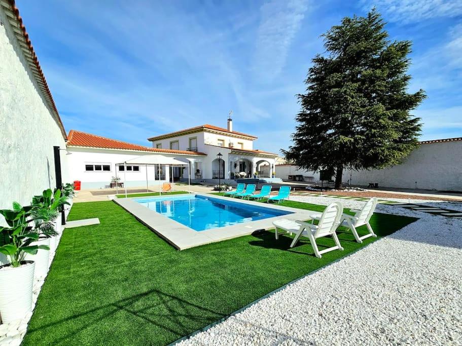 un patio trasero con piscina y césped verde en La casa del árbol, en Fuentidueña de Tajo