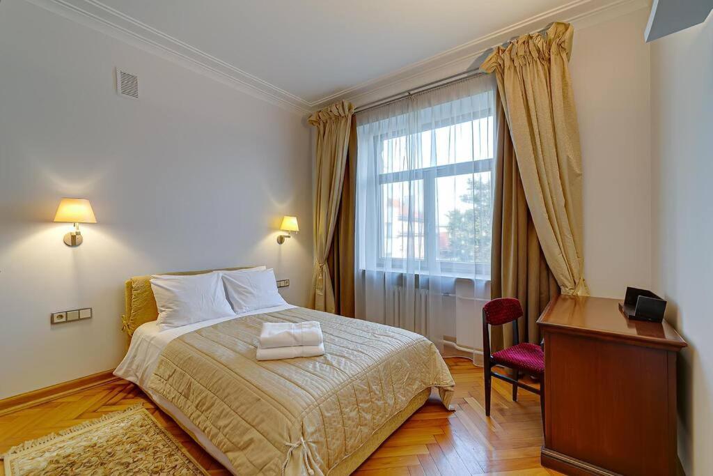 um quarto com uma cama, uma secretária e uma janela em Arena Park Apartment em Kaunas