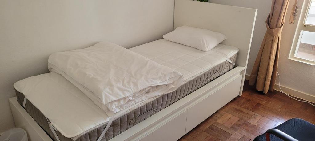 een klein bed met witte lakens en een kussen erop bij Cozy Room near Metro & Airport in Lissabon