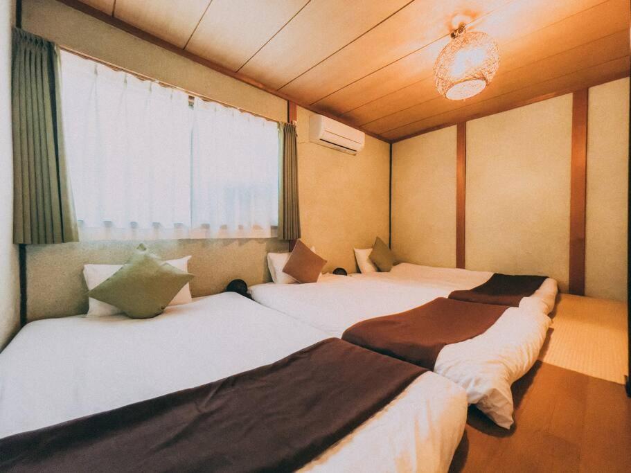 two beds in a room with a window at *Fortune House*動物園前站只要步行2分鐘 日式一户建 可6人入住 in Osaka