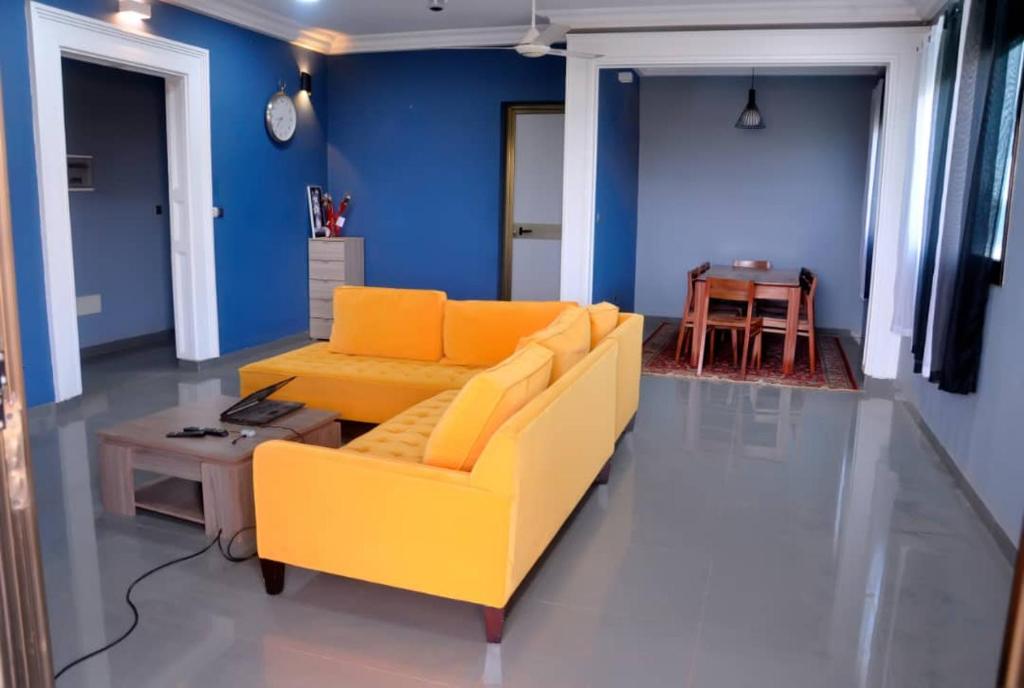 uma sala de estar com um sofá amarelo e uma mesa em Résidence Sampo em Ouagadougou