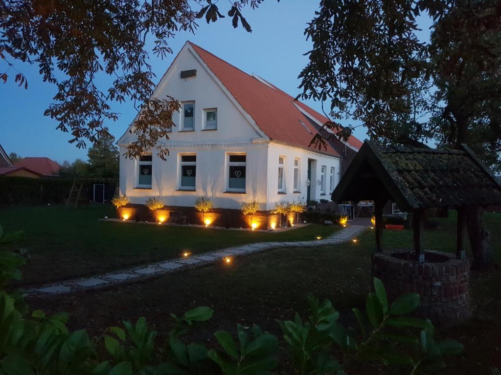 ein weißes Haus mit Lichtern im Hof in der Unterkunft Ferienwohnung Geeske im Gulfhof in Krummhörn