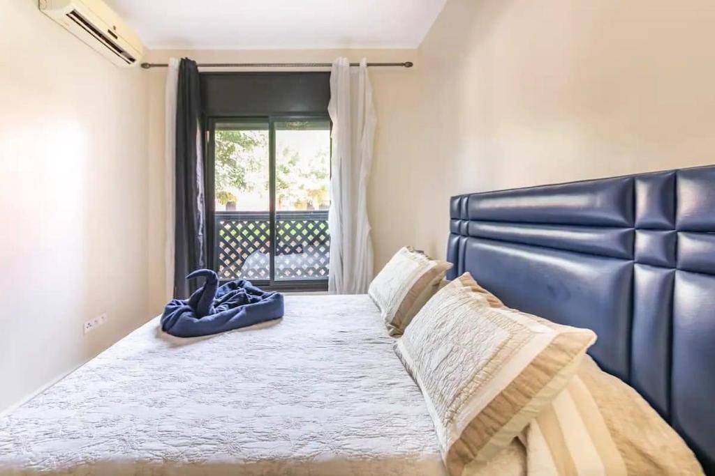 a bedroom with a large bed with a blue leather headboard at Appartement gueliz de luxe in Marrakesh