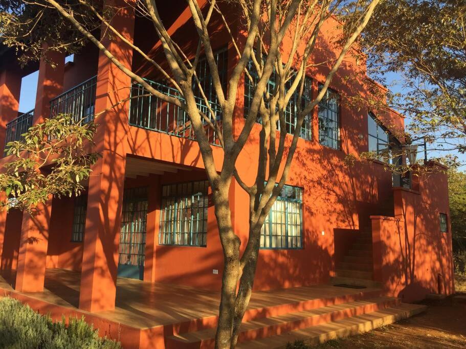een oranje gebouw met een boom ervoor bij Gongali House - Karatu Rewilded in Karatu