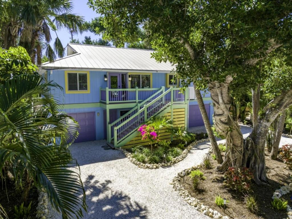a blue and yellow house with a porch and trees at Dancing Dolphin home in Captiva