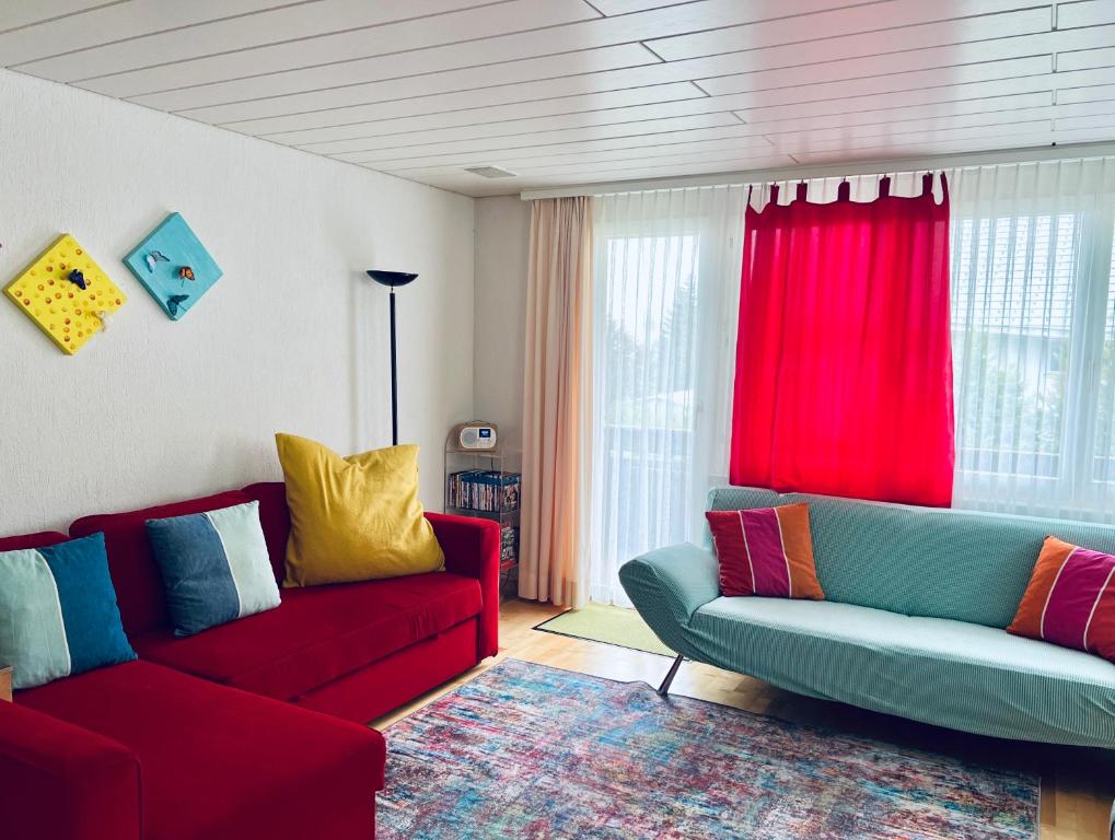 a living room with two red couches and red curtains at Casa Lilly - CharmingStay in Flumserberg
