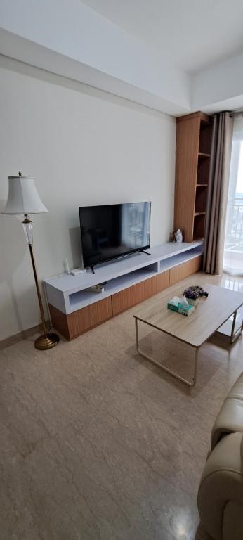 Una sala de estar con televisión y una mesa de café. en Lincoln Tower Podomoro Apartment, en Medan