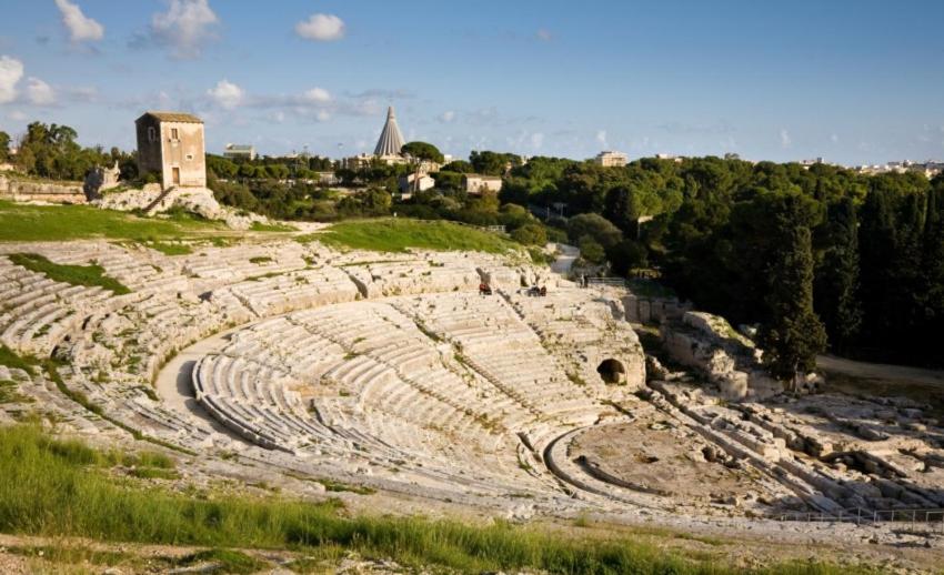 an ancient amphitheater with a building in the background at casa antica grecia in Siracusa