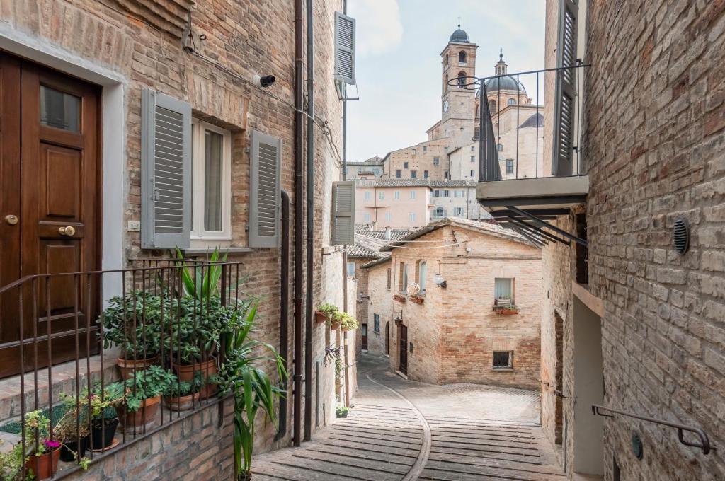 un vicolo in un centro storico con una torre dell'orologio di Urbino Historical Central Studio! a Urbino