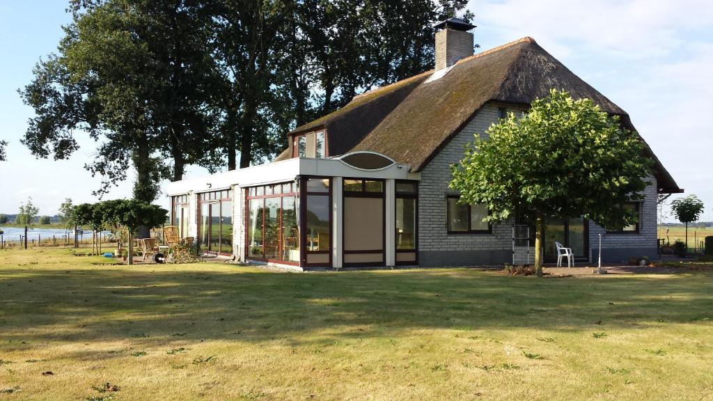 a small house with a thatched roof on a field at B&B Krachtwijk in Soest