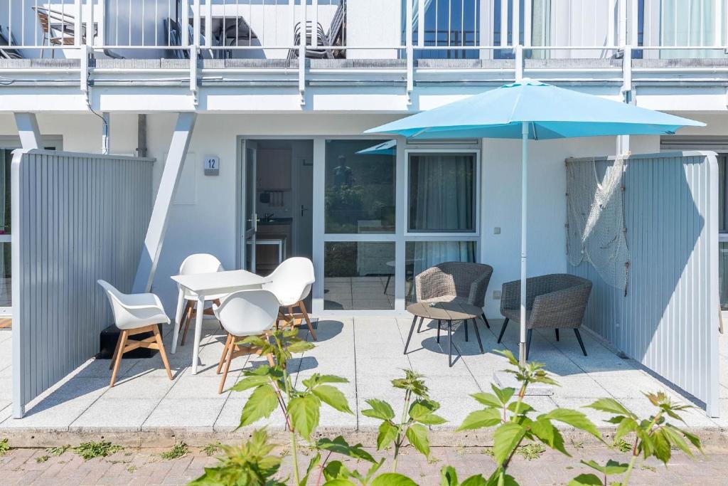 a patio with a table and chairs and an umbrella at Haus Seeblick Wohnung 12 Easy Ocean in Wohlenberg