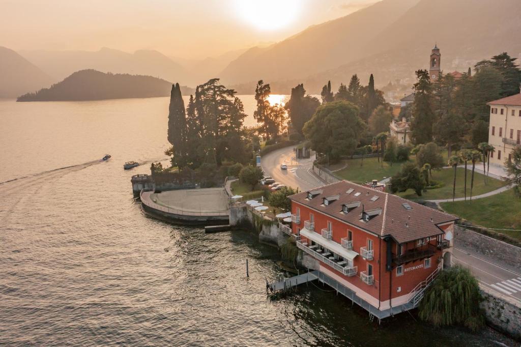 a house on the shore of a lake with the sun setting at La Darsena Boutique Hotel & Restaurant in Tremezzo