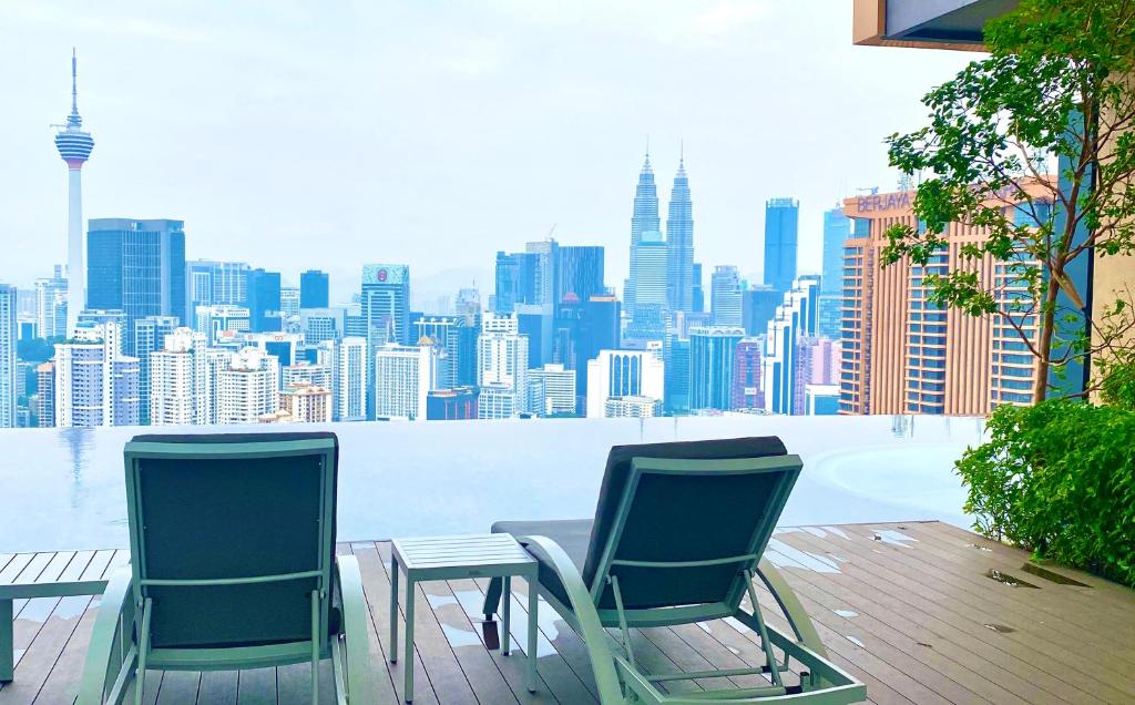 two chairs and a table with a view of a city at Lalaport Suites At Lucentia Bukit Bintang City Center in Kuala Lumpur