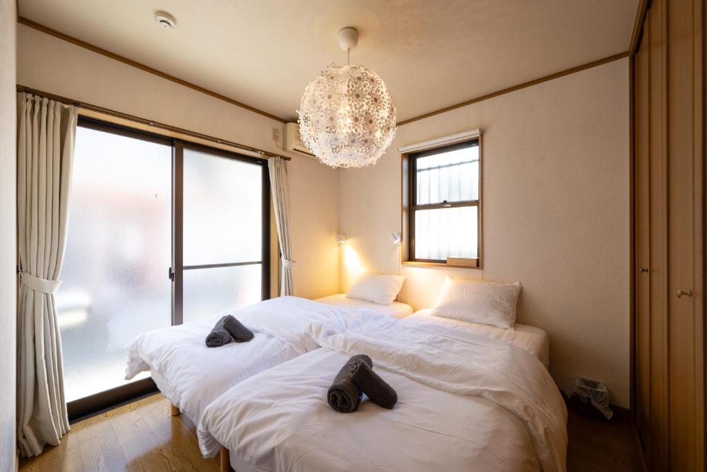 two beds in a bedroom with a chandelier at VILLA MorE in Tokyo